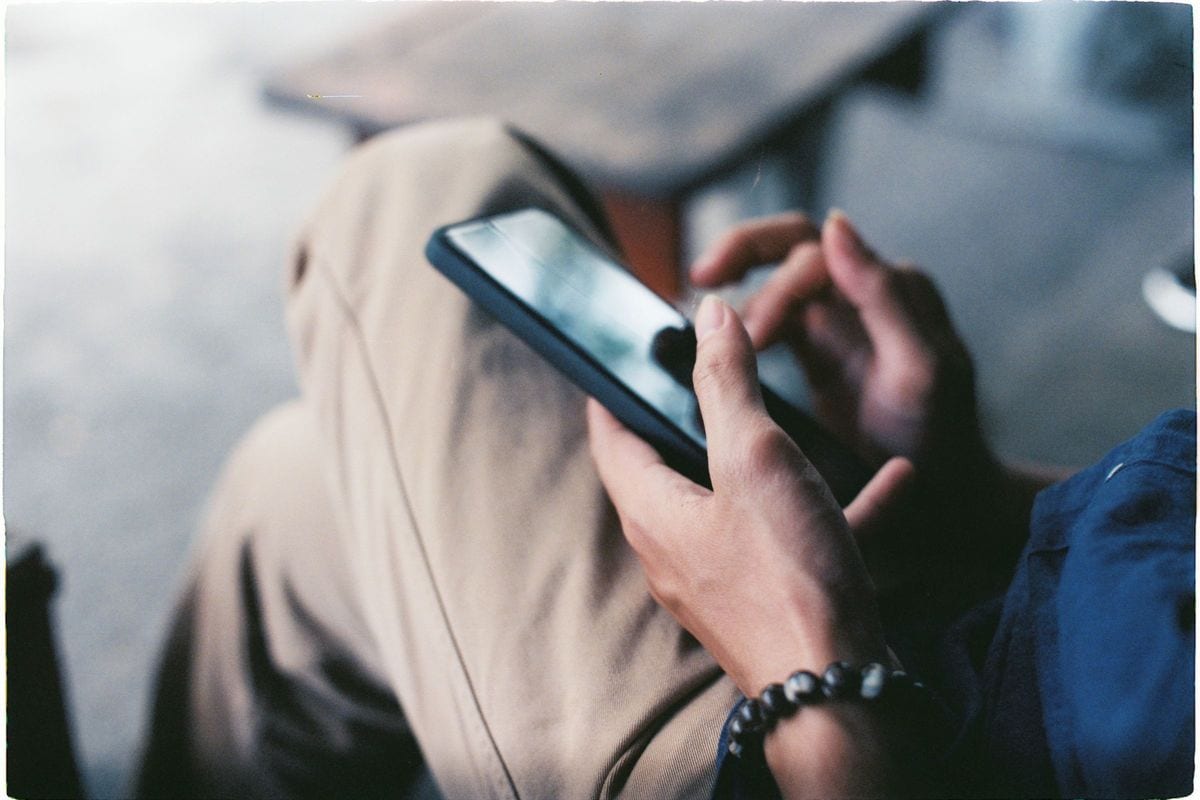 Close-up of hands scrolling on a smartphone: an ad has about a second here, and the ones that stop the scroll win the auction for less