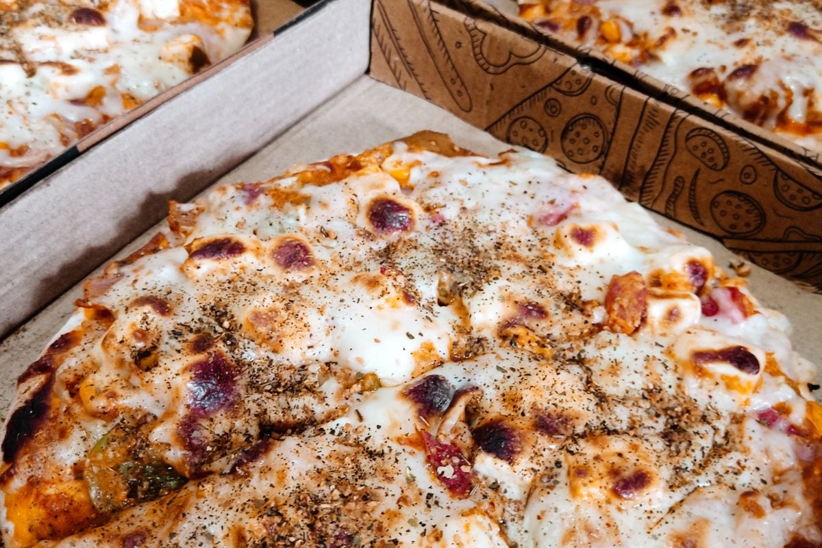 Freshly baked pizzas in open cardboard delivery boxes: the product Domino's remade on camera before it asked customers to try again