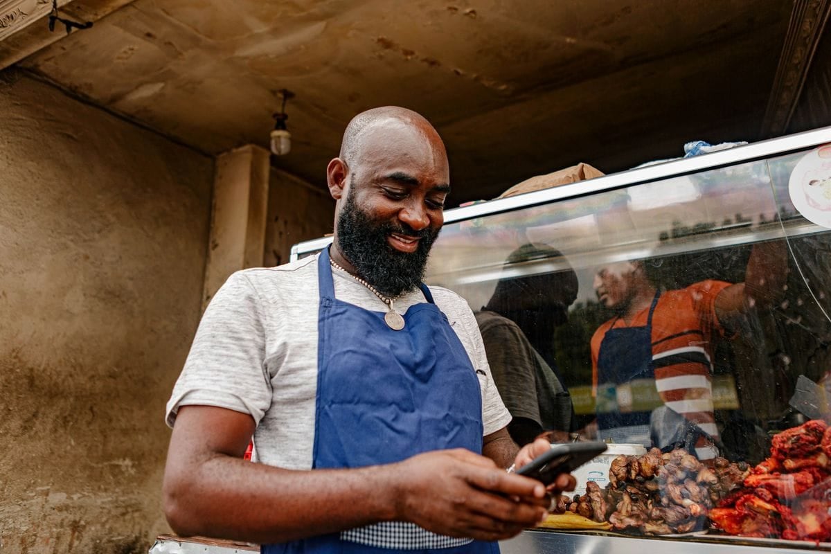 A man in an apron reading comments on his phone: the replies under a post often say more than the reaction count