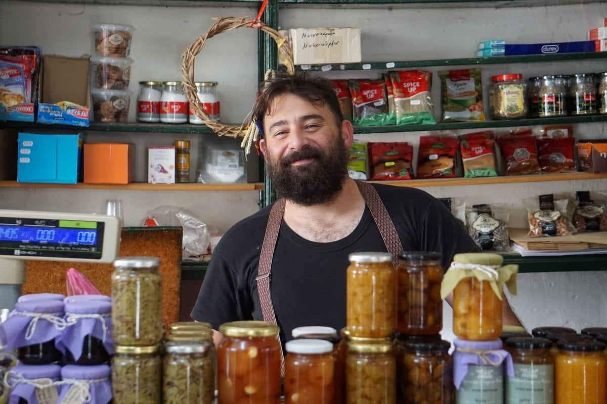 A smiling shop owner behind shelves of homemade preserves: a company page post that shows the real people and the real work