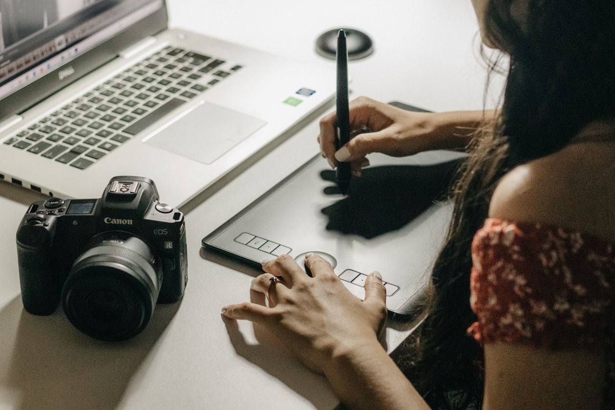 A designer working at a graphics tablet beside a laptop and a camera: a test batch is built around one question before any design starts